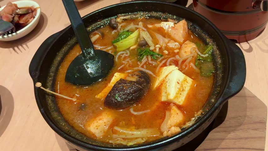 Spicy Salmon Jjigae Korean Stew with Tofu and Enoki Mushroom in Stone Pot, Hot Asian Soup