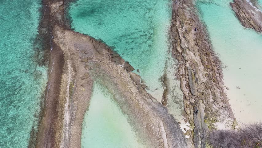 Aerial view of rocky formations and crystal clear turquoise water along the tropical coastline of Hoarafushi, Haa Alif, Maldives.
