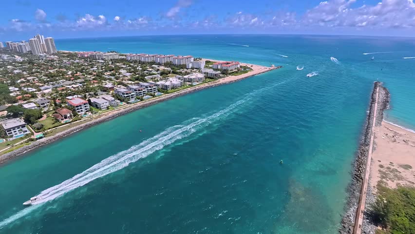 Aerial view of Palm Beach Inlet with boats cruising through turquoise waters along the sandy coastline and residential buildings, Palm Beach, Florida, United States.