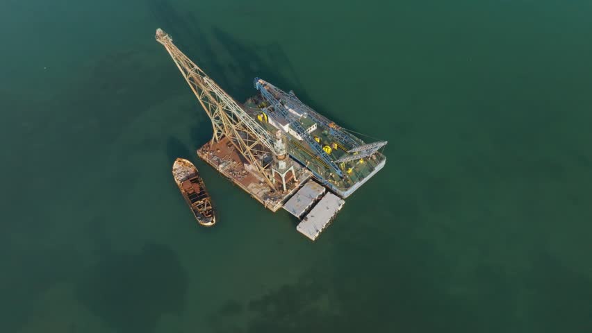 Aerial view of a large industrial floating crane barge and a vessel in the port of Augusta Syracuse, Sicily, Italy.