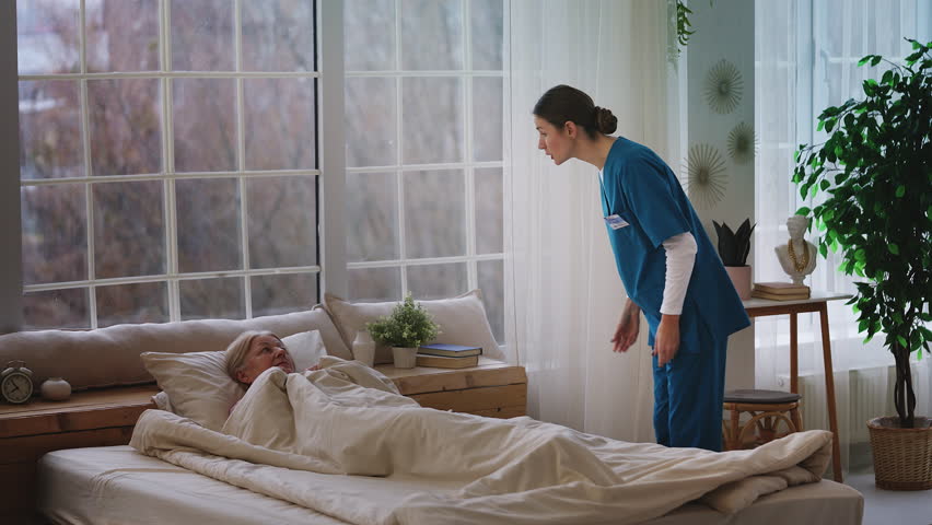 Aggressive young nurse shouting at upset elderly woman patient in hospital