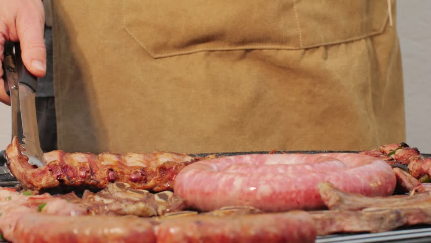 Traditional spanish barbeque, big sausage chorizo botifarra, pork and beef ribs on grill with fire, american style cooking, chef grilling meat fat food, steaks and sausages on bbq.