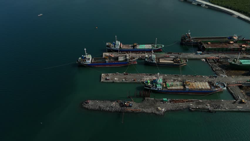 Aerial view of a harbour with docked ships. Turquoise water surrounds the port