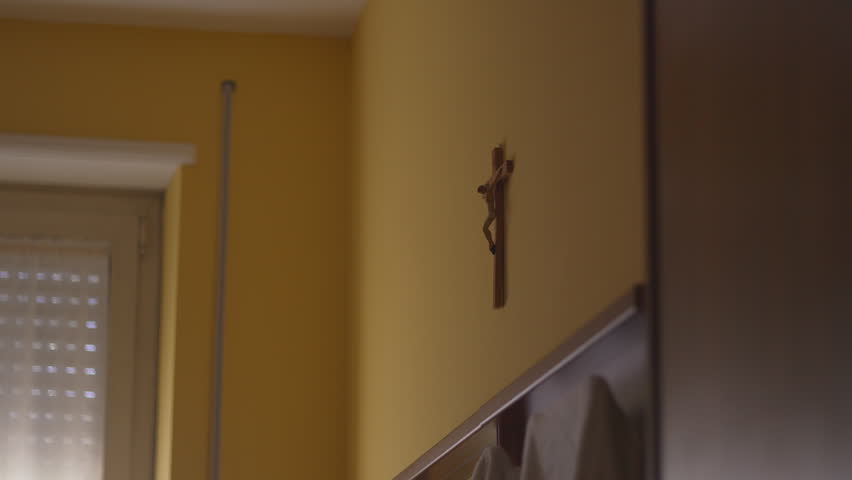 Wooden Crucifix Hanging on Yellow Wall in Home Interior Above Door Frame with Warm Religious and Spiritual Symbolism