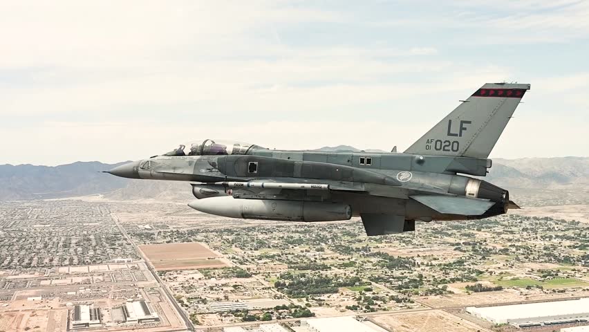 Armed Belgian F-16 Fighter Jet Banks Above Expansive Desert Cityscape During Advanced Combat Training Mission Exercises.