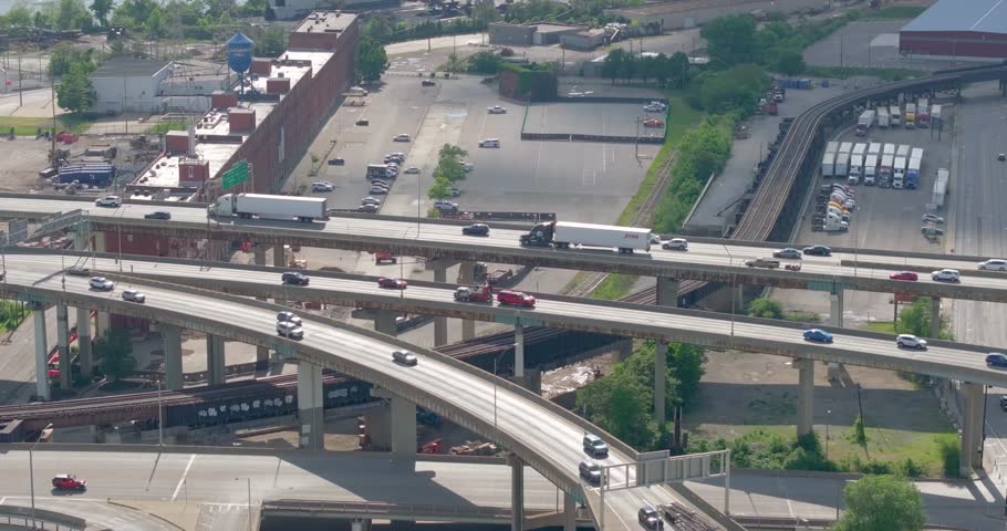 Aerial view of a complex highway interchange with cars and trucks driving on multiple levels of overpasses near industrial buildings in Cincinnati, Ohio, United States.