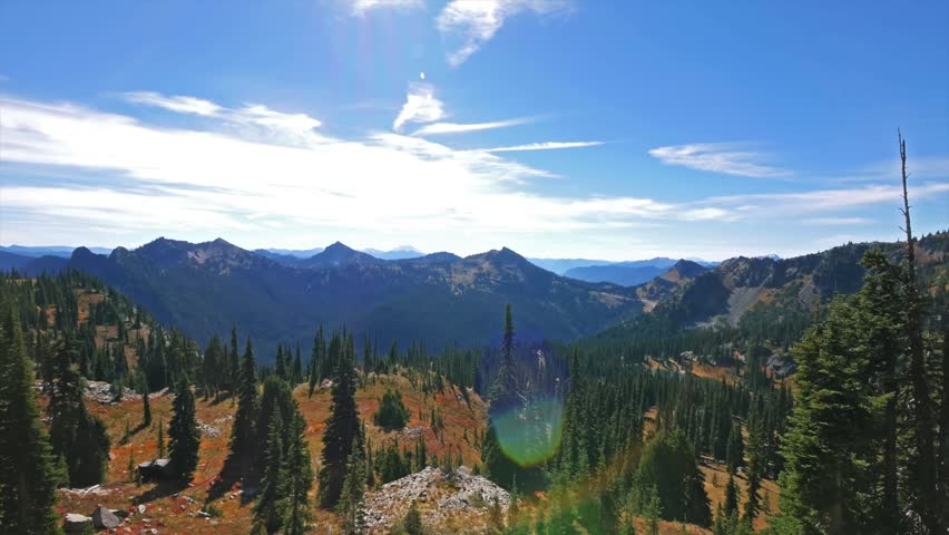 sun-drenched panoramic view of the Cascade Mountains and evergreen forests as seen from the Pacific Crest Trail near Sheep Lake and Sourdough Gap in Mount Rainier National Park, Washington State.