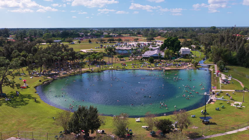 Warm mineral springs attraction with calm turquoise water, swimmers, and sunlit landscape, representing recreation, tourism, and holistic health treatments.