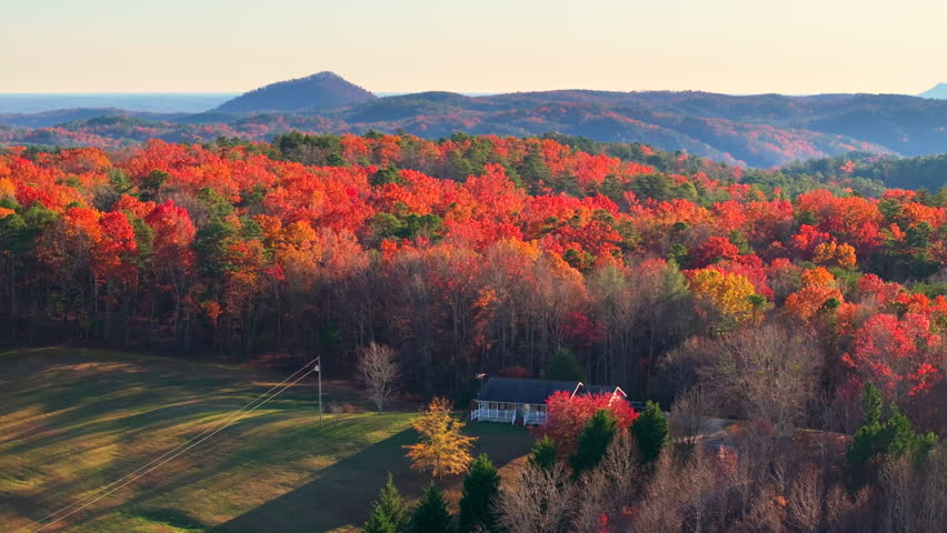 Appalachian mountain rural landscape with orange and yellow forest trees. Tennessee houses appear between rolling hills and colorful foliage