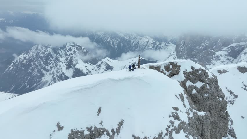 Aerial view of two people standing on a snowy mountain ridge in Parco Naturale Paneveggio Pale di San Martino Primiero San Martino di Castrozza, Trentino-Alto Adige, Italy.