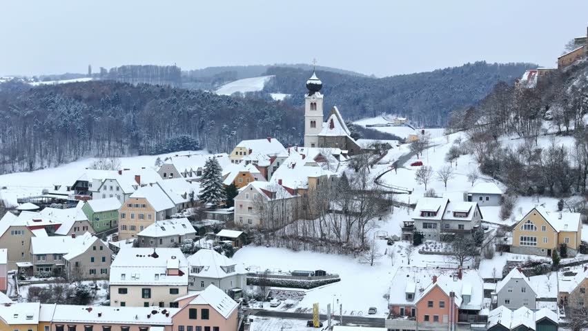 Aerial view of the snow-covered village of Riegersburg with its parish church and historic houses nestled among winter hills in Riegersburg, Styria, Austria.