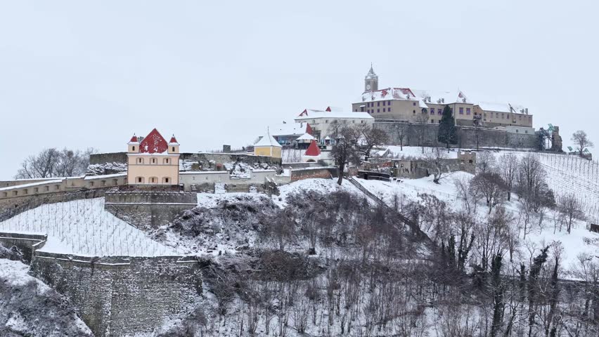 Aerial view of Riegersburg Castle with its medieval fortifications and red-roofed buildings on a snow-covered hill in Riegersburg, Styria, Austria.