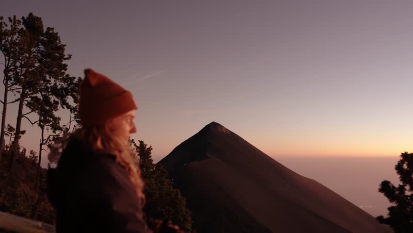 Traveler watching Fuego volcano at sunset from Acatenango basecamp in Guatemala