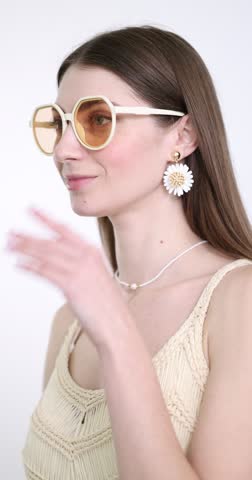 Woman wearing stylish earring, sunglasses and necklace on white background