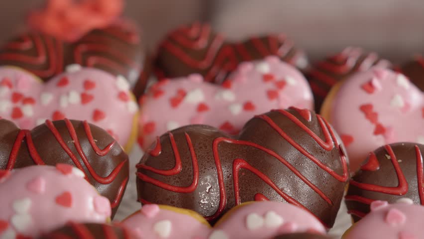 Heart-shaped pastries with chocolate and pink strawberry glaze. Decorated with small sugar hearts for Valentine