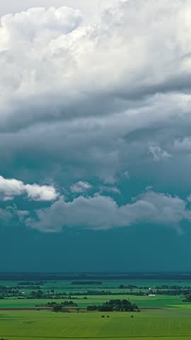 Clouds swirl in the sky over green meadows.