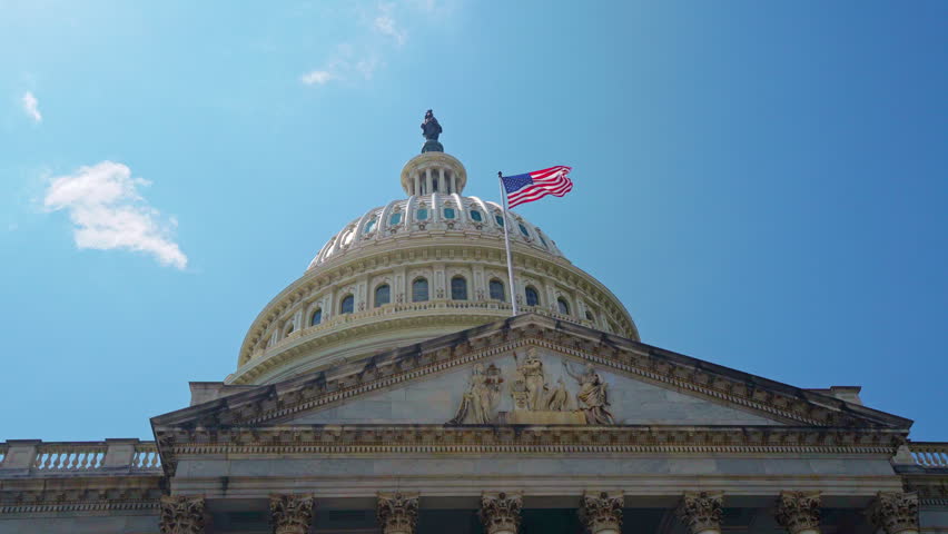 American flag waving in sky near US Congress. American flag on capitol dome. American flag for patriotism symbol. American flag in Washington DC.