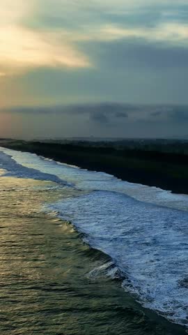 Vertical sunset coastline with waves and clouds