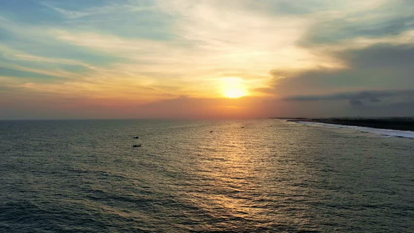 Sunset over calm ocean and distant coastline