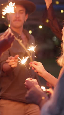 Outdoor, dance and friends with sparklers at festival, party and listening to music concert together. Night, event and people with fireworks for celebration, gathering and happy for festive season