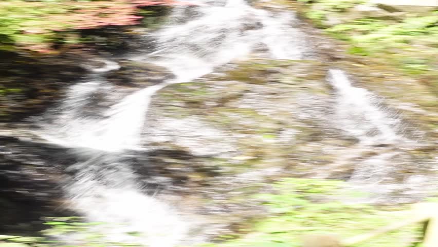 Waterfall cascading down rocky cliff surrounded by lush greenery