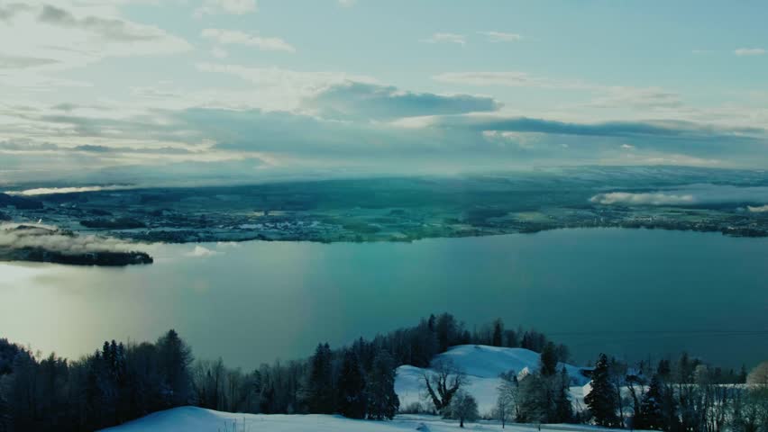 Aerial panorama of snowy hills and large lake during winter morning