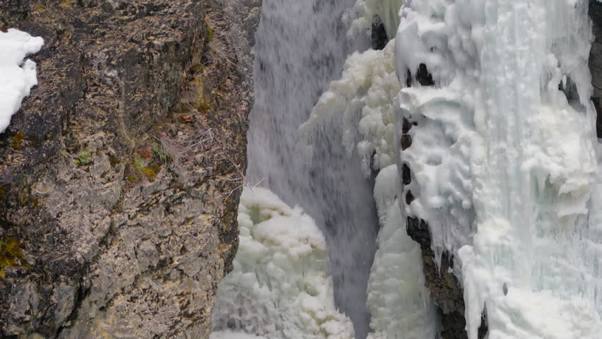Fast-flowing green creek over rocks, snow on edges, winter atmosphere.