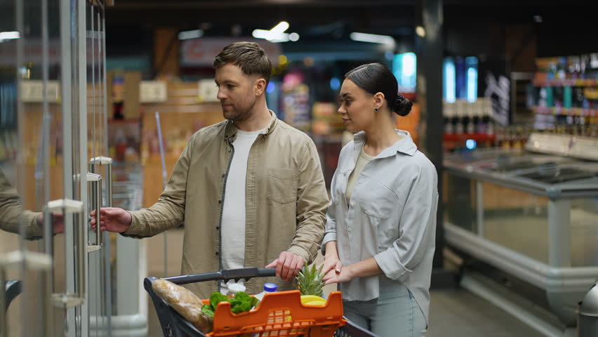 Young couple choosing fresh eggs at the supermarket refrigerator