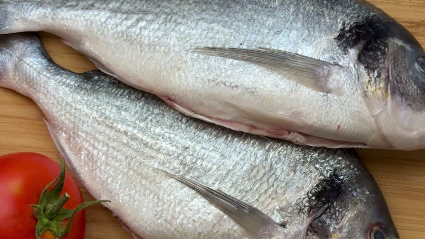 Two raw sea bream fish with vegetables. A close-up shot of raw fish, cooking delicious food at home.