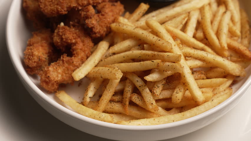 Delicious plate of chicken fingers and french fries with a dipping sauce isolated on a white background, fa01