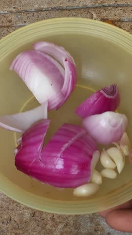 Raw ingredients plate with sliced red onions and whole garlic cloves