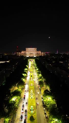 Aerial view of the Palace of the Parliament illuminated at night in Bucharest, Romania. Cinematic drone shot of the massive communist-era landmark during nighttime