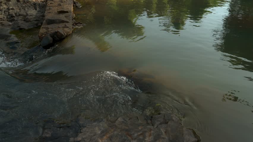 Panning from the top of Maak Ngaew falls looking down over the edge to the pool of water below the falls.
