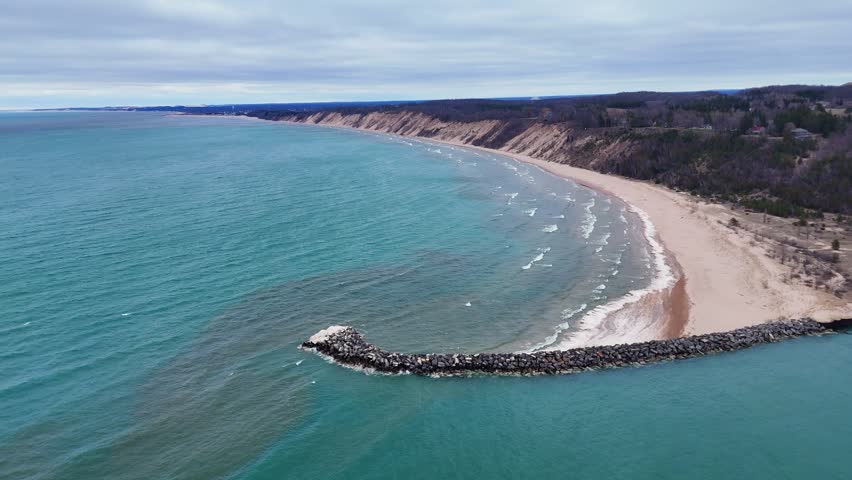 Lake Michigan coastline featuring pier and sandy beach on a cloudy day near Ludington, Michigan, USA