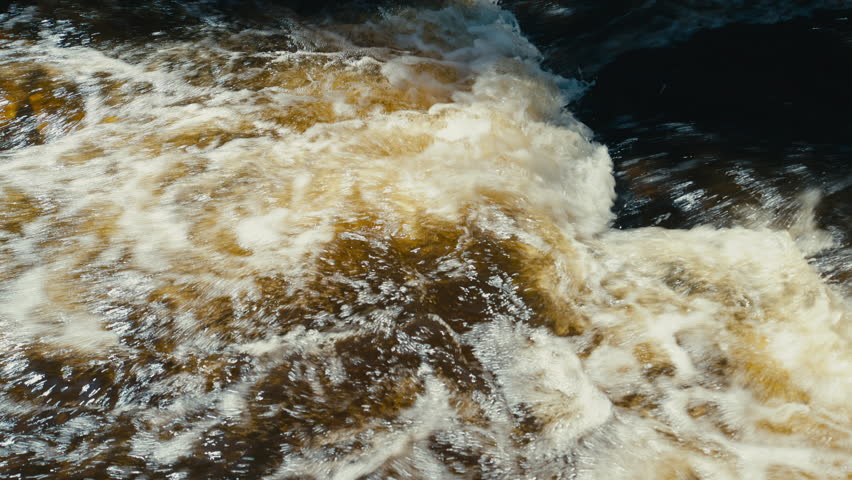 Sunlit rapids churn into golden foam and dark swirling currents, creating an energetic close-up of turbulent freshwater with vivid texture and motion.