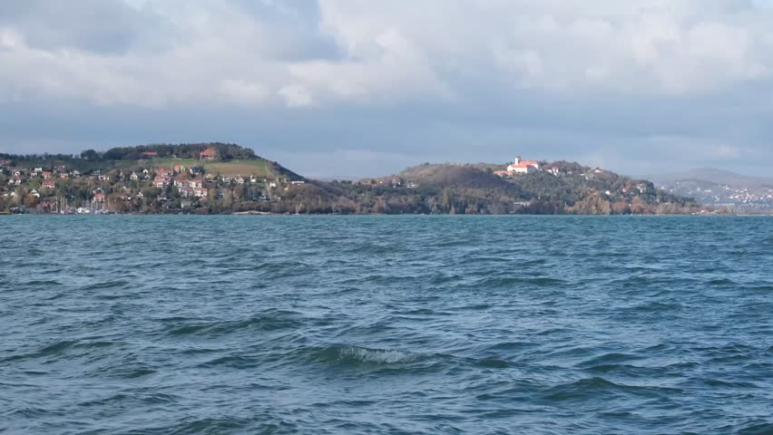 The famous Benedictine monastery on the Tihany peninsula on a sunny autumn day. Blue wavy water of Lake Balaton in the foreground. Real time scenic landscape from Hungary.