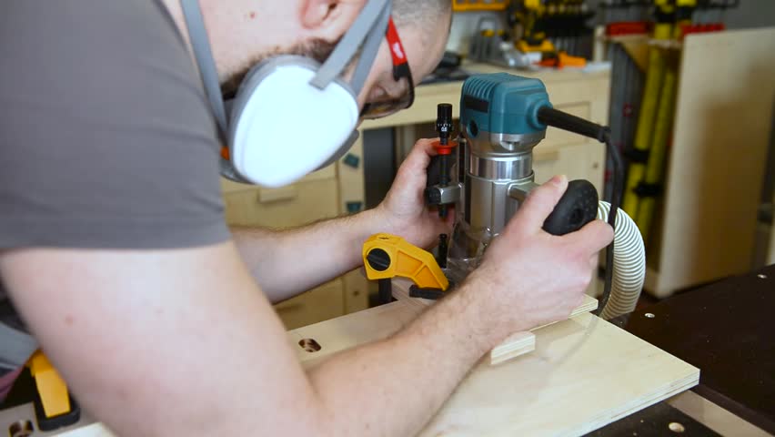 Skilled carpenter flexing his muscles while using router at construction site. Wood router in action smoothly cutting into a wooden surface. shot highlights woodworking craftsmanship