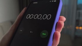 Hand holds smartphone with stopwatch running. Timer advances from seconds to minutes on a dark screen. Mobile time tracking for workout and productivity. - Powered by Shutterstock - Get 15% off with code: PIKWIZARD15