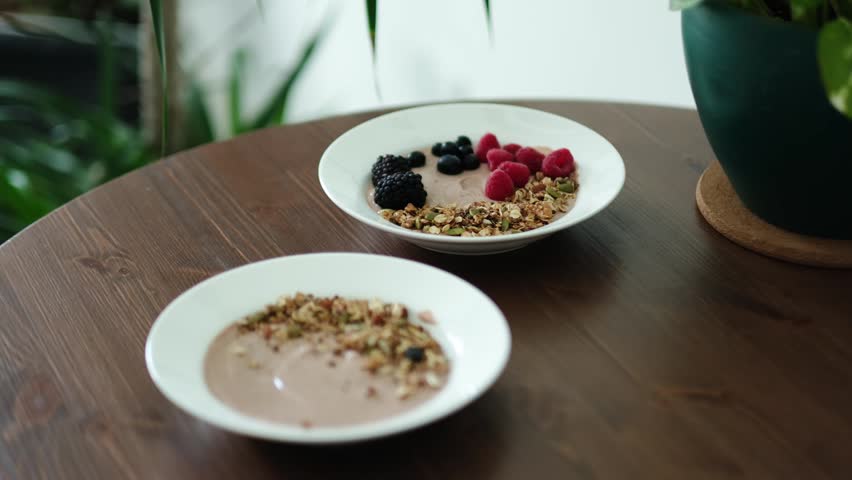 Woman making healthy breakfast with fresh berries on protein rich Greek yogurt bowl