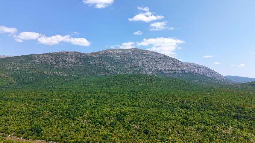 Aerial view of the scenic mountain landscape and lush green forests in Croatia under a clear blue sky