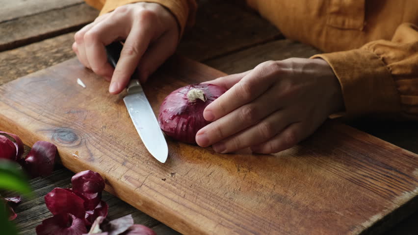 Female hands peeling red onion on wooden board. Cooking, meal prep. 