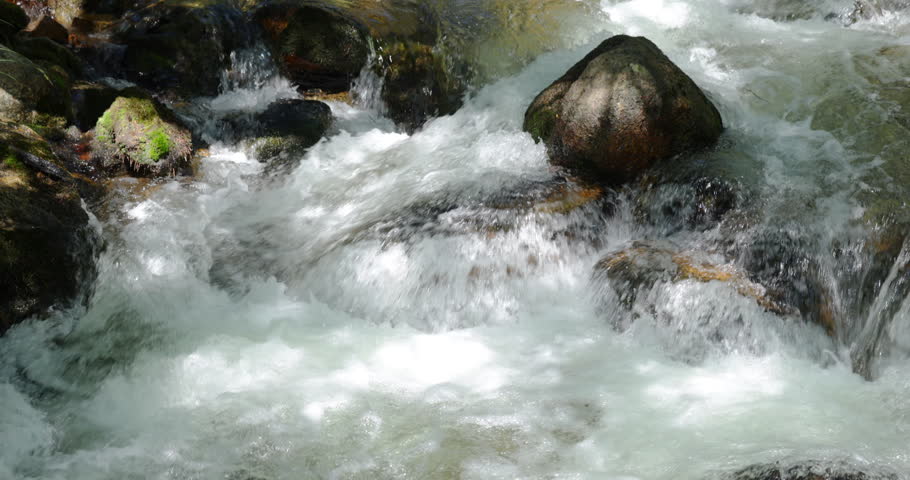 Close up of rushing river water with white foam and bubbles in slow motion