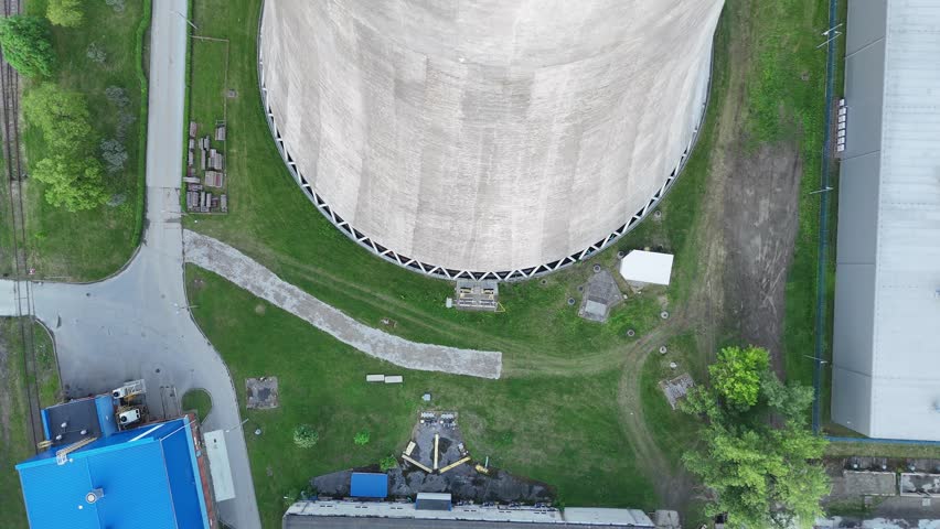 Aerial view of cooling tower at thermal power plant with steam rising, showcasing the structure