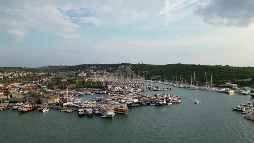 Historical castle walls and fishing boats in the harbor of Sigacik