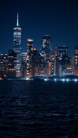 Prominent skyline of New York, USA at night. Admiring gorgeous metropolis from the river cruise. Vertical video.