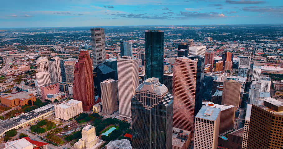 Modern downtown Houston, Texas, USA from drone footage going up. Vast low-rise panorama of the city with lots of greenery at backdrop.