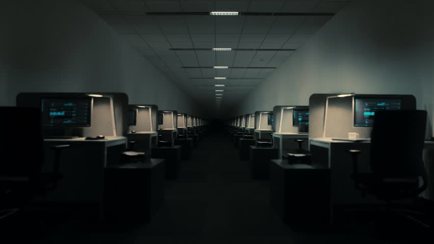 Dolly shot moving forward in a dark and empty office hallway with rows of computer workstations