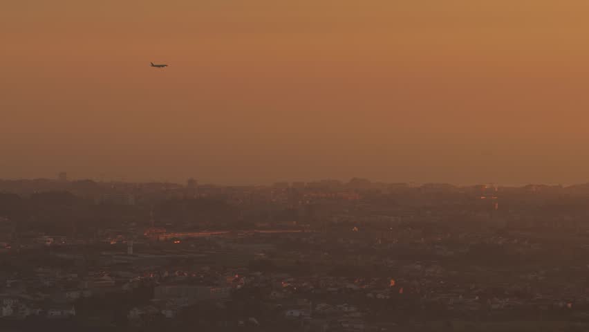 Airplane flying over the city of Porto at sunset. Plane on airport aproach.