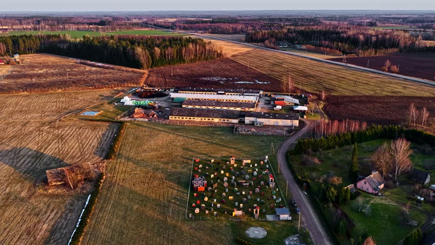 Vibrant paintball field and an old farm in a rural landscape at sunset in aerial view