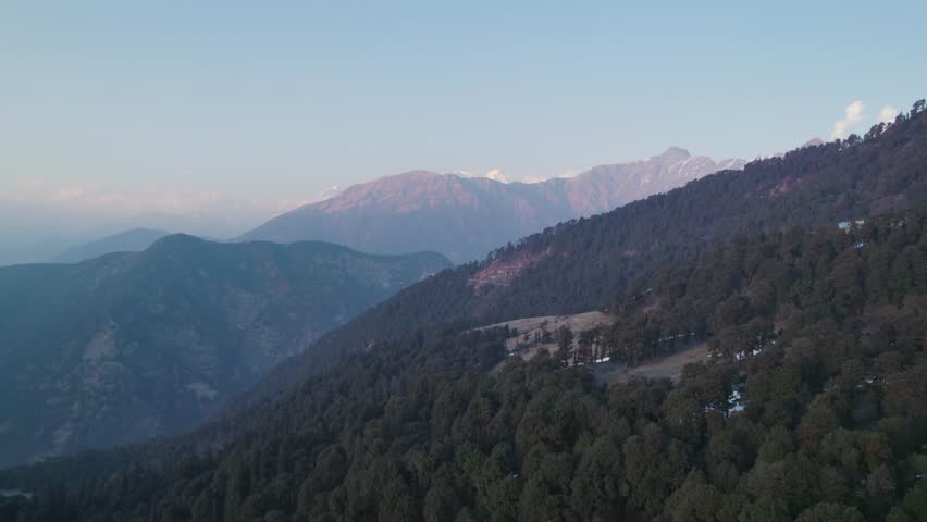 Aerial view of the lush evergreen forests and rolling mountain ridges of Chopta Tungnath under a clear sky in Chopta, Uttarakhand, India.